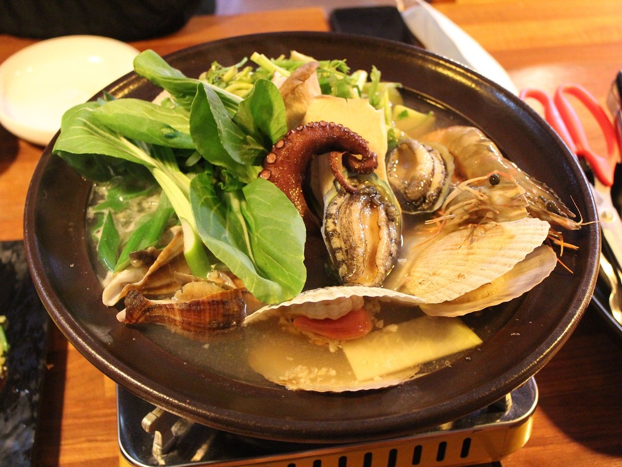 Cooked pot of haemultang (spicy seafood stew) with various greens