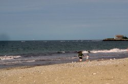 Adult and child walking along the shore of East Matunuck State Beach